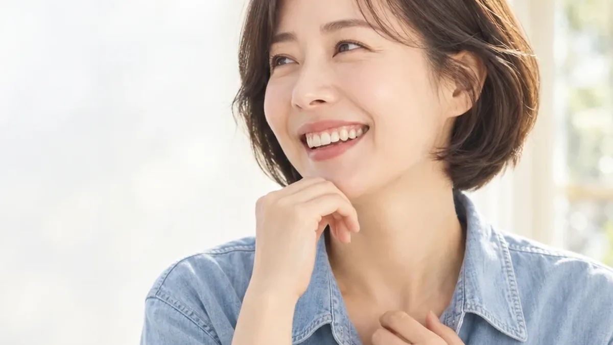 창가에서 턱을 괴고 웃는 데님 셔츠 여성