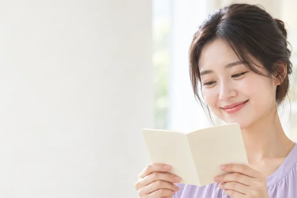 소액결제현금화 준비물 창가에서 작은 수첩을 펼쳐 보는 보라색 카디건 여성 24시 바로